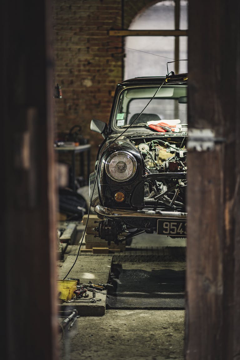 A classic Mini Cooper undergoing repair in a Paris garage, capturing vintage automobile charm.