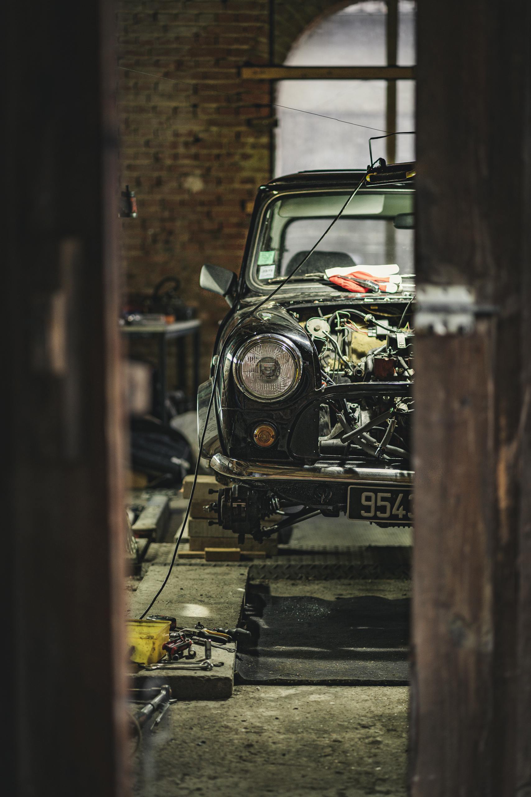 A classic Mini Cooper undergoing repair in a Paris garage, capturing vintage automobile charm.