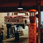 Classic car elevated in a Bangkok garage with retro elements highlighting vintage automotive culture.