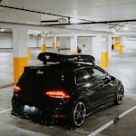 Stylish black car with a roof rack parked in a dimly lit underground garage.