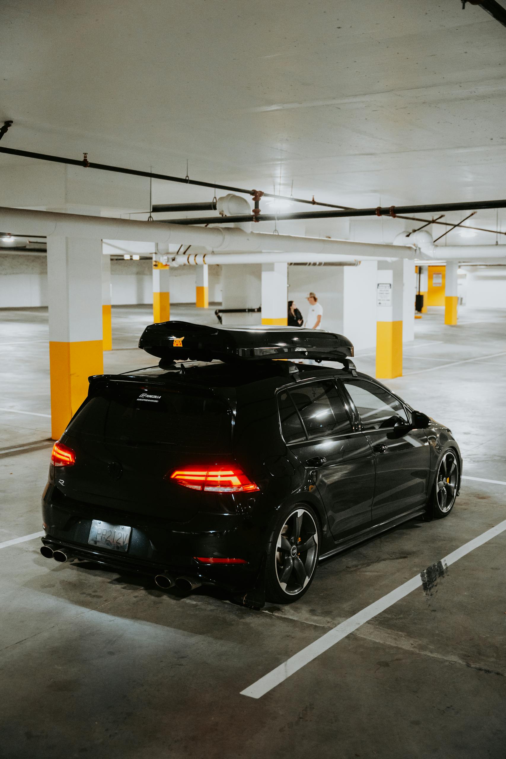 Stylish black car with a roof rack parked in a dimly lit underground garage.